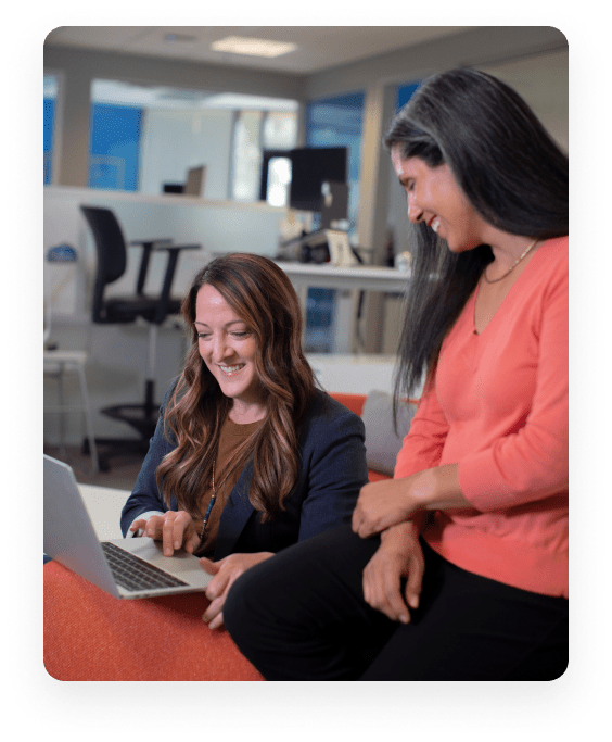 Two colleagues collaborating on a laptop, representing Infotel UK's commitment to digital accessibility and equal social policies.